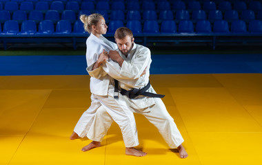 Martial arts. Sparing Portners. Sport man and woman in white kimono train judo throws and captures...