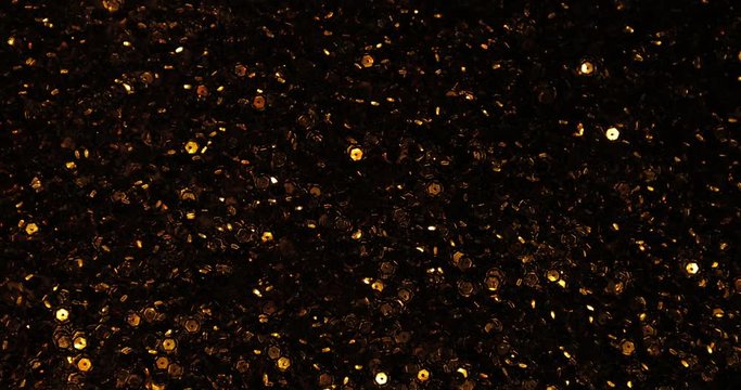 Magical view of shimmering golden sequins in the dark. Stunning effect of flickering golden highlights.