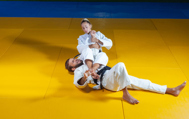 Martial arts. Sparing Portners. Sport man and woman in white kimono train judo throws and captures...