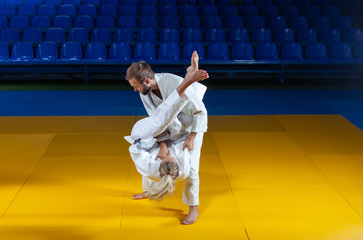 Martial arts. Sparing Portners. Sport man and woman in white kimono train judo throws and captures...