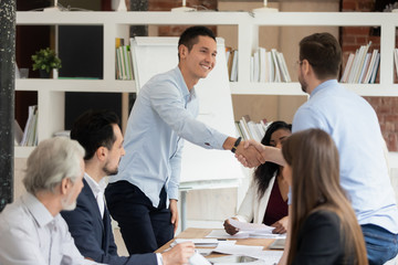 Smiling male employees handshake greeting at meeting