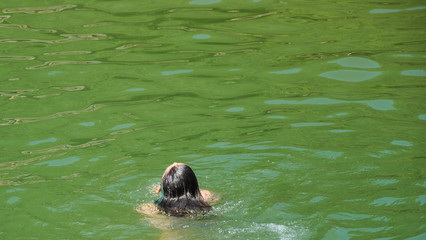 Obraz premium Cabeza de mujer por detrás con pelo mojado dentro del río