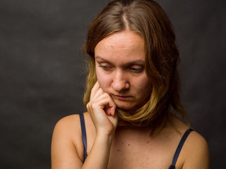 Portrait of young woman, no make up, low key, brown dark hair, no retouch making expressions
