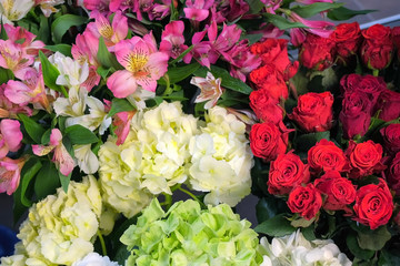Beautiful different sorts of flowers roses, astra, azalea, alstroemeria, hydrangea, peonies, eucalyptus with water drops in vases in flower shop for sale, closeup view. Floral business concept.