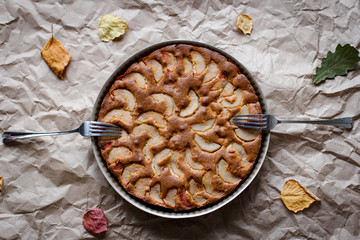 top view of the kitchen table with fruitcake, two forks, autumn leaves on brown crumpled wrapping paper