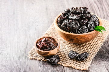Prunes in wooden bowl on old rustic table. dried plums on table. Heap of prunes on old board.