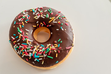 donut with chocolate icing and sprinkles on light background