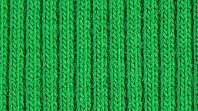 Textile background - green cotton fabric with jersey (ribbing) structure. Weave pattern of threads close up. Macro shoot.