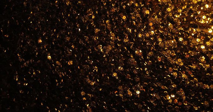 Lots of sparkling gold sequins arranged as a background. Each sequin shimmers with golden highlights and the background looks magical and gives a sense of celebration