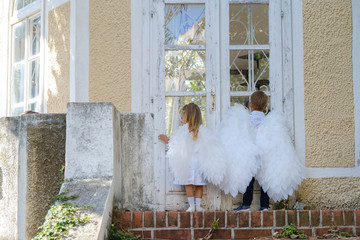 Сhildren dressed as angels stand in front of a closed door