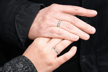 Wedding rings on his hands. An elderly couple got married. Happy family. Family outdoors.