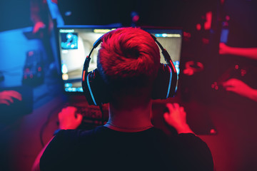 Professional gamer playing online games tournaments pc computer with headphones, Blurred red and...