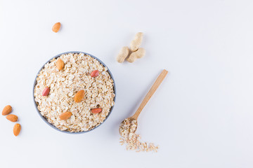 Dry oatmeal and nuts on white background. Ingredients for healthy breakfast: almonds, peanuts and oatmeal. Copy space