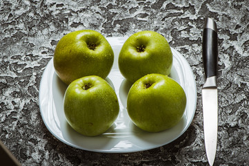 Apples in a plate than a knife. Fresh yellow apples.