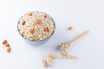 Dry oatmeal and nuts on white background. Ingredients for healthy breakfast: almonds, peanuts and oatmeal. Copy space