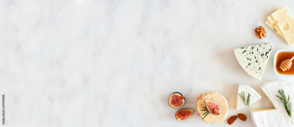 Aufkleber corner border of a selection of cheeses, figs, nuts and honey. above view banner on a white marble b