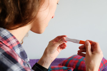 Young woman holds a pregnancy test with a positive result