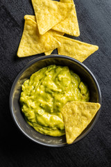 Corn nacho chips and avocado dip. Yellow tortilla chips and guacamole