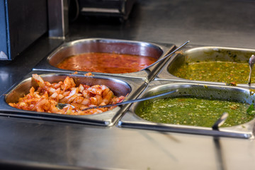 ingredients at a falafel bar with metal vegetable tongs and saucesbar with metal vegetable tongs and sauces