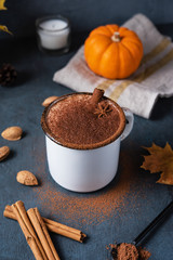 Aroma spice coffee latte drink with pumpkin,  milk foam, cinammon and chocolate  on the dark blue table.Autumn morning. Image in vertical orientation
