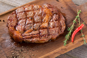 Rib eye steak on wooden board, closeup