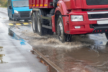 street lighting. it's raining. a puddle formed on it a car will pass.