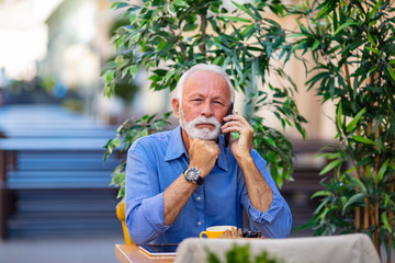 Senior man using smart phone in cafe . Successful senior businessman in cafe. Senior man in cafe using smartphone. Senior man speaking by cellphone