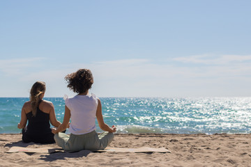 Fototapeta premium Yoga teacher and friend doing exercises next to the beach. Concentration and relaxing moment. 