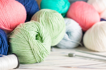 Knitting hobby composition with colorful yarn balls and needles on white wooden background. Close up