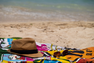 Pareo de playa , sombrero y gafas en una playa desierta junto al mar en el atardecer.