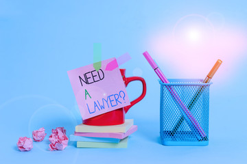 Word writing text Need A Lawyer Question. Business photo showcasing Legal problem Looking for help from an attorney Cup pens holder note banners stacked pads paper balls pastel background