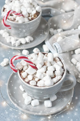 Cups of creamy hot chocolate with melted marshmallows and  candy cane for cristmas holiday