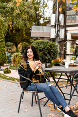 Fototapeta na wymiar beautiful girl in yellow sweater drinking coffee outside