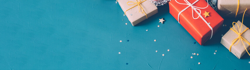 Winter holidays. Cropped flat lay of beige and red gift boxes, star and round shape glitter on teal...
