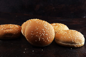 Fresh homemade burger buns with sesame on dark background