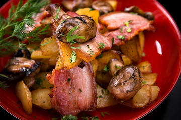 Fried potatoes with bacon and mushrooms on a plate
