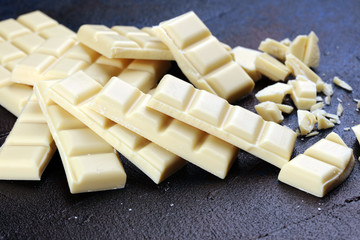 white broken chocolate and cocoa bar. Pieces of white chocolate on rustic background