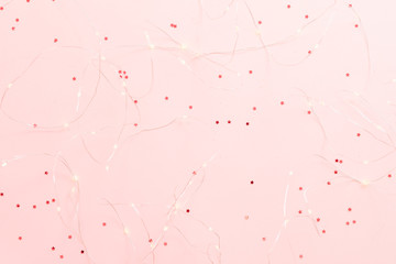 Winter holiday decoration. Top view of warm white LED string lights on star pattern pink background. Copy space.