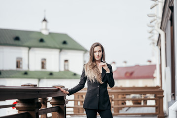 Naklejka na ściany i meble Business girl in a black suit against the background of the city