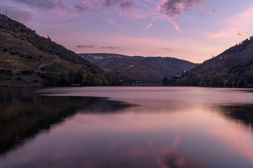 The smooth waters of the River Duoro  at sunset, with the terraced valley walls brimming with vineyards