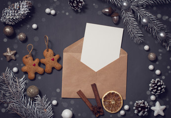 Christmas theme with fir branches, Santa handmade toy, cones, cookies and candies, on rustic dark wooden background viewed from above, top, in snow greeting card with space for text. Postcard design