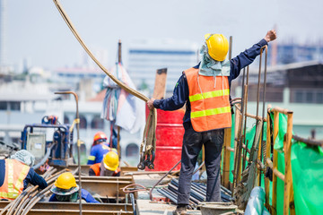 Construction team working at height site. Construction workers raising hands to signal construction...