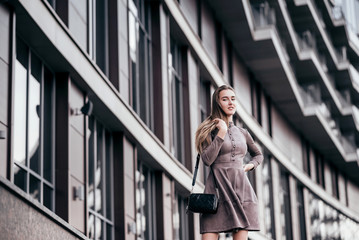 Fototapeta premium A young girl walks near the office with a handbag on her shoulder
