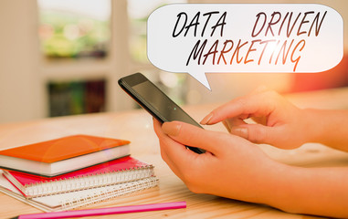 Conceptual hand writing showing Data Driven Marketing. Concept meaning Strategy built on Insights Analysis from interactions woman using smartphone and technological devices inside the home