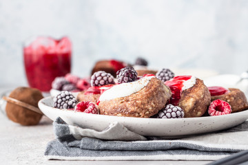 Chocolate cottage cheese pancakes or fritters with sour cream and frozen berries (raspberry and blackberry). Traditional Ukrainian and Russian cuisine. Syrniki. Healthy and diet breakfast or dessert.