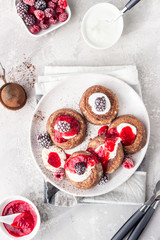 Chocolate cottage cheese pancakes or fritters with sour cream and frozen berries (raspberry and blackberry). Traditional Ukrainian and Russian cuisine. Syrniki. Healthy and diet breakfast or dessert.