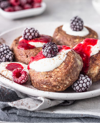Chocolate cottage cheese pancakes or fritters with sour cream and frozen berries (raspberry and blackberry). Traditional Ukrainian and Russian cuisine. Syrniki. Healthy and diet breakfast or dessert.