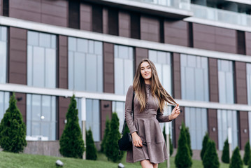 Fototapeta premium A young girl walks near the office with a handbag on her shoulder