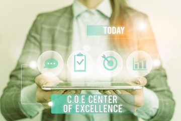 Writing note showing Coe Center Of Excellence. Business concept for being alpha leader in your position Achieve Female human wear formal work suit presenting smart device