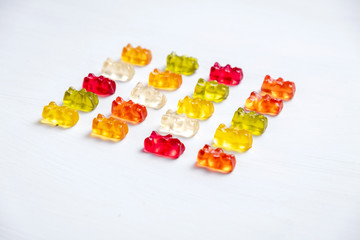 Children's vitamins in the form of bears are arranged in rows.  A lot of multi-colored jelly sweets...